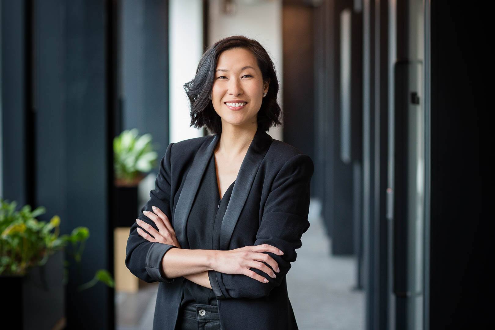 Corporate portrait photoshoot for BCG in Fitzrovia showing a woman in black jacket with crossed arms in an office corridor.